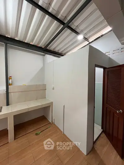 Compact kitchen area with tiled countertop and adjacent bathroom in a modern home.