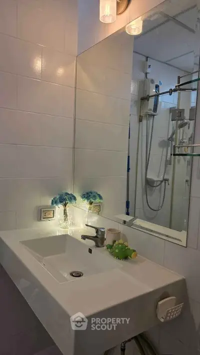 Modern bathroom with sleek sink and shower, accented by decorative flowers.