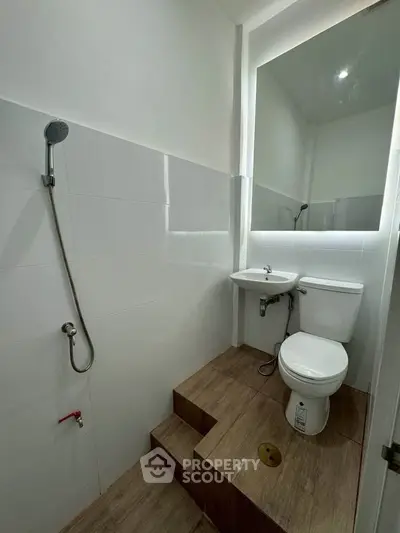 Compact bathroom with elevated toilet and sink, featuring modern fixtures and minimalist design.