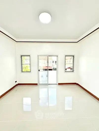 Spacious and bright living room with large windows and glossy tiled floor.