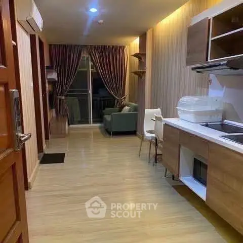 Modern apartment interior with open kitchen and cozy living area, featuring stylish lighting and wooden flooring.