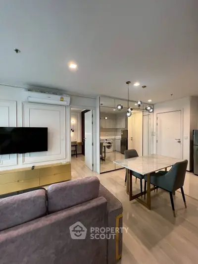 Modern living room with stylish dining area and wall-mounted TV in a chic apartment.