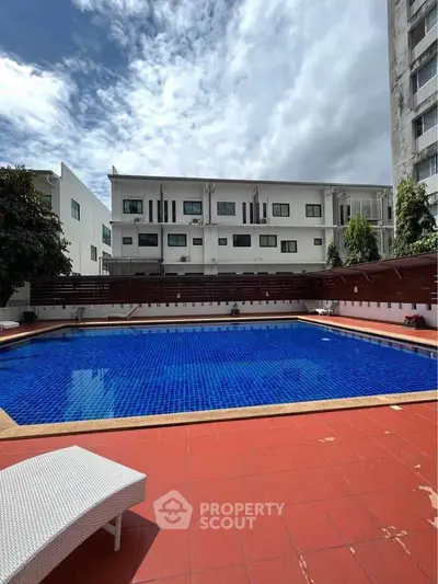 Spacious outdoor pool area with modern apartment backdrop, perfect for relaxation and leisure.