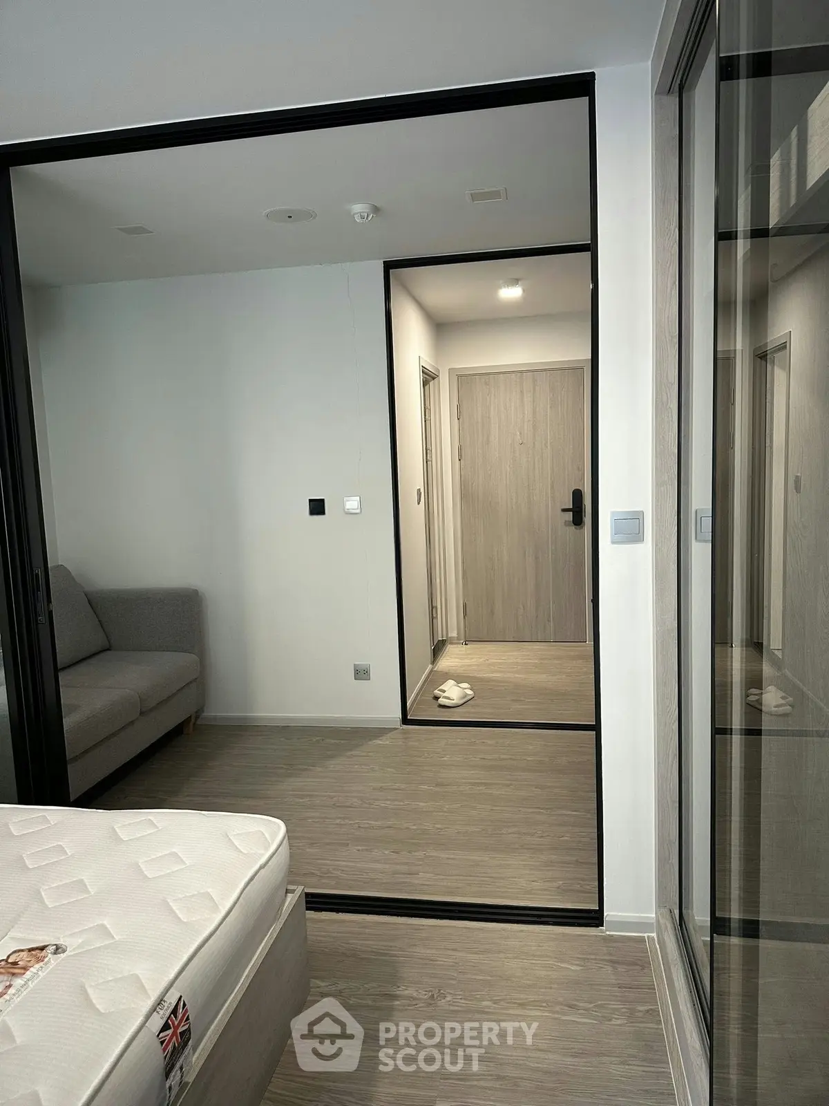 Modern bedroom with sleek design and glass partition, featuring a cozy sofa and stylish flooring.