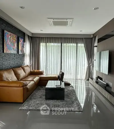 Modern living room with leather sofa and large TV, featuring sleek design and natural light.