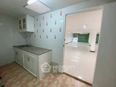 Spacious kitchen with open layout and tiled flooring leading to bright living area.