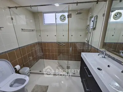 Modern bathroom with glass shower and sleek vanity in contemporary home.