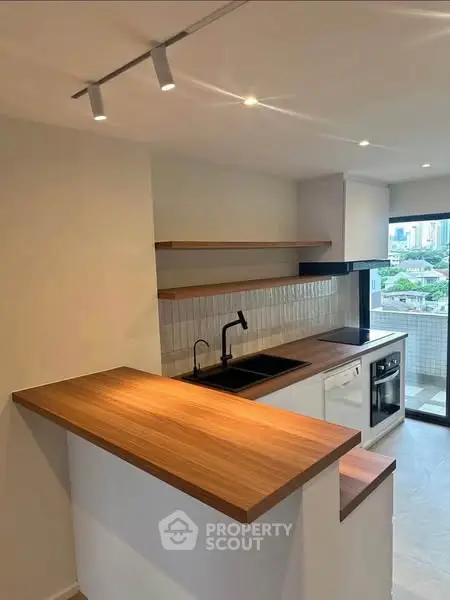 Modern kitchen with wooden countertops and city view, featuring sleek design and ample natural light.