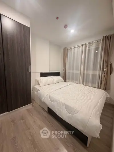 Modern bedroom with cozy bed and stylish wardrobe in a well-lit apartment.
