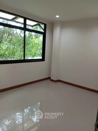 Bright empty room with large window and tree view, perfect for customization.