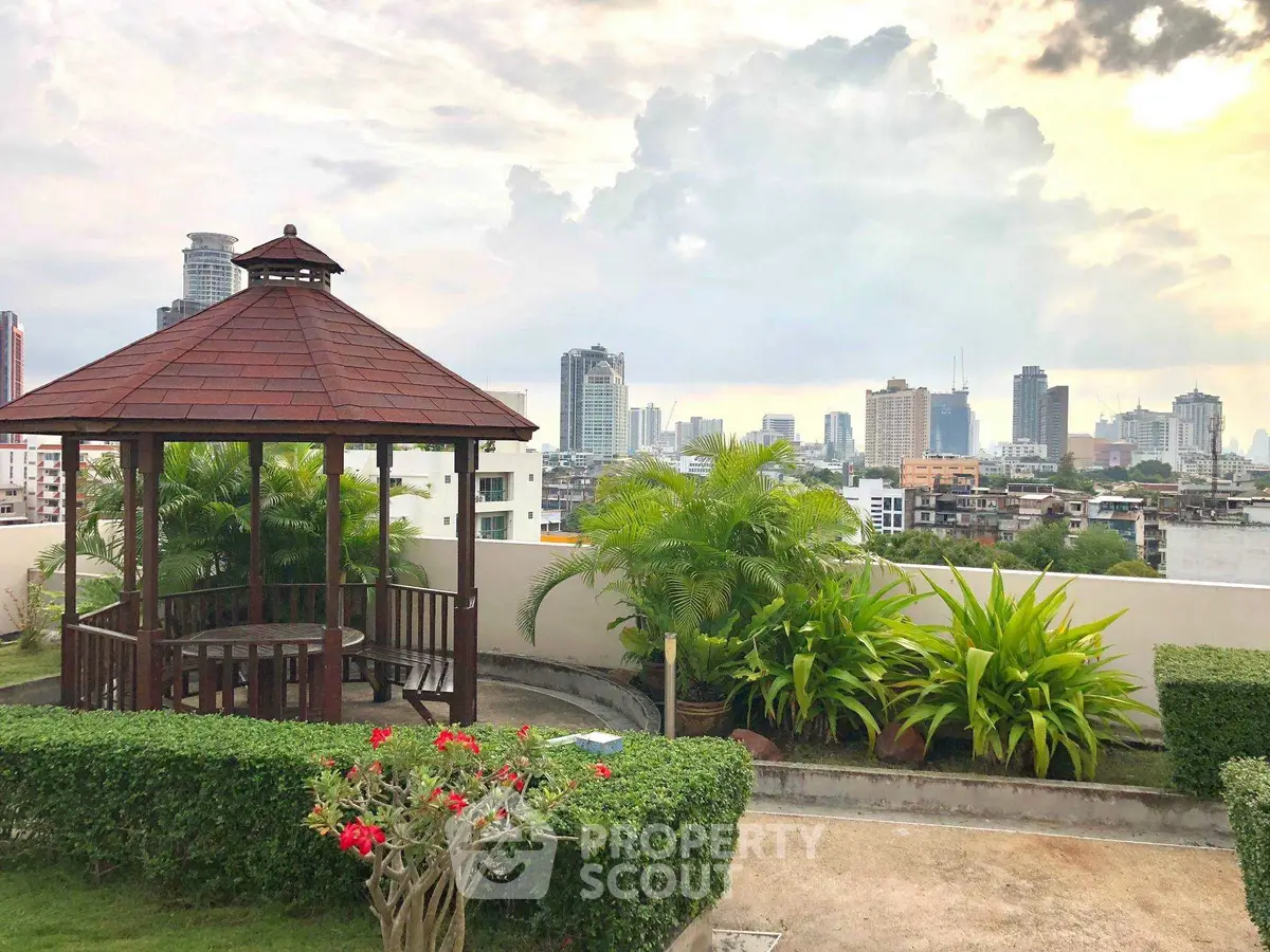 Stunning rooftop garden with city skyline view, featuring a charming gazebo and lush greenery.