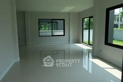 Spacious sunlit living room with large windows and glossy floors