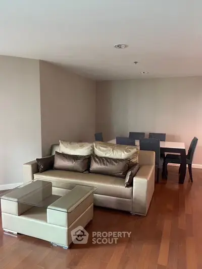 Modern living room with stylish furniture and dining area, featuring hardwood floors and neutral tones.