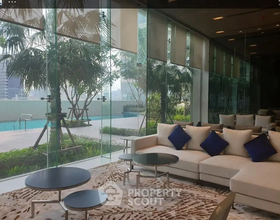 Luxurious modern living room with floor-to-ceiling windows overlooking a serene pool and garden area.