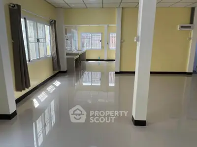 Spacious open-plan living area with large windows and glossy tiled floors, perfect for modern living.