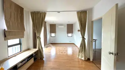 Spacious living room with wooden flooring and large windows for natural light.