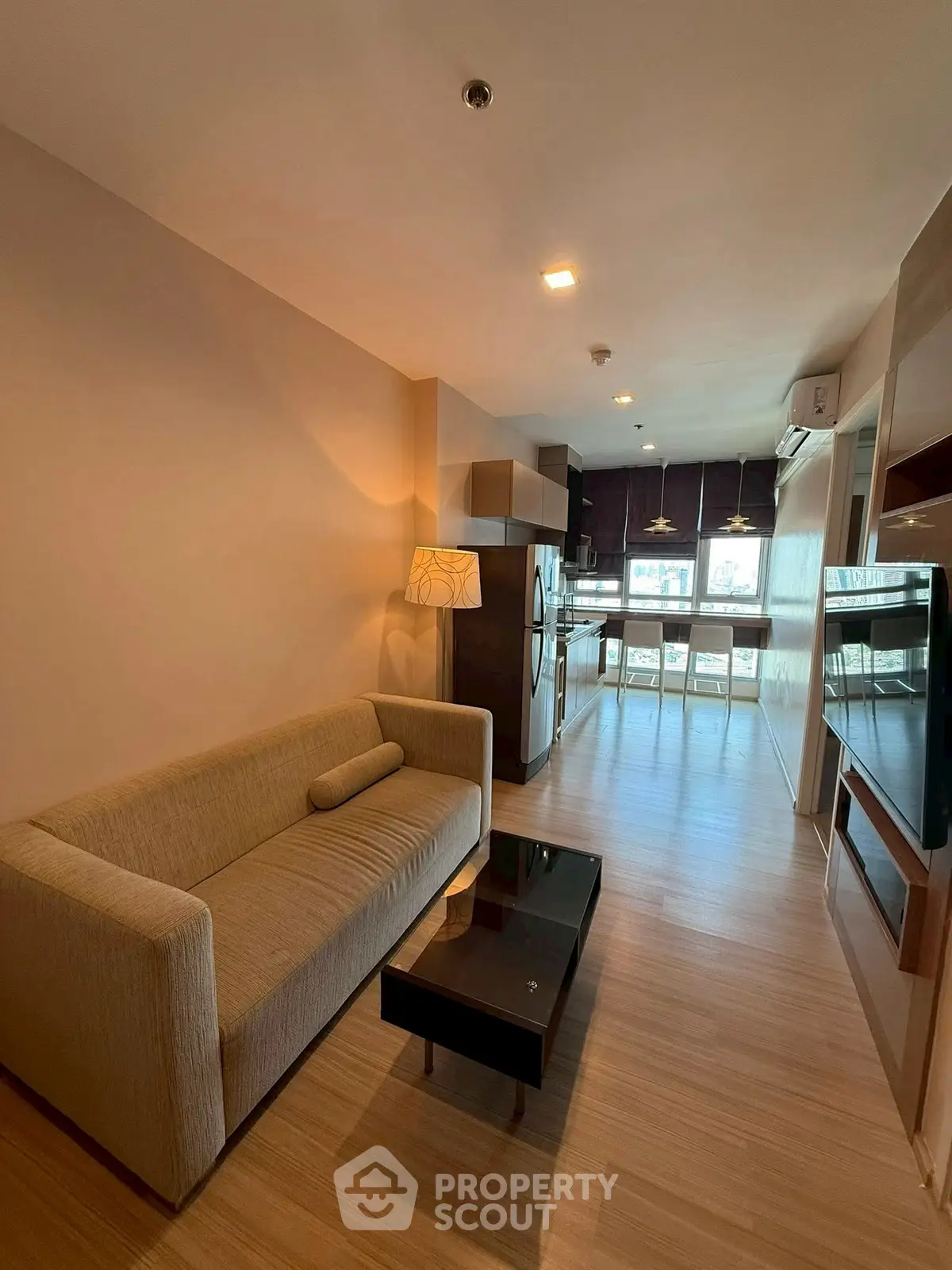 Modern living room with cozy sofa and open kitchen layout, featuring sleek appliances and stylish decor.