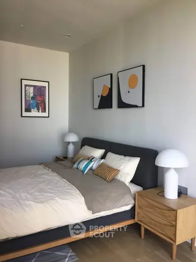 Modern bedroom with stylish decor and cozy ambiance, featuring elegant artwork and contemporary furniture.