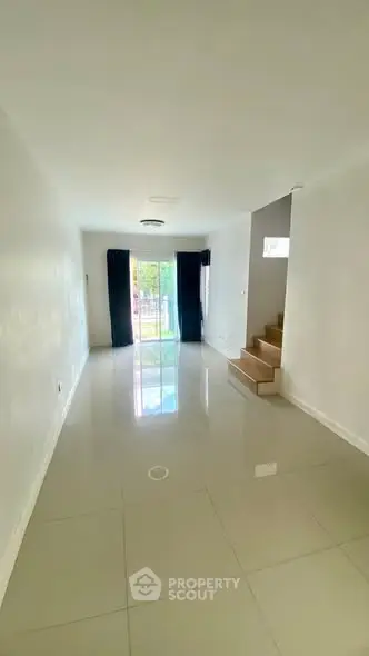 Spacious living room with glossy tiled floors and large window for natural light.