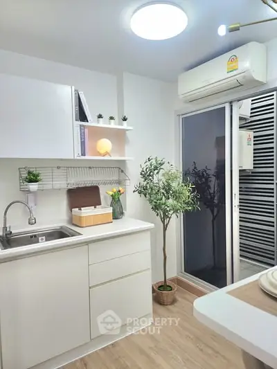 Modern kitchen with sleek white cabinets and air conditioning, featuring a small balcony.