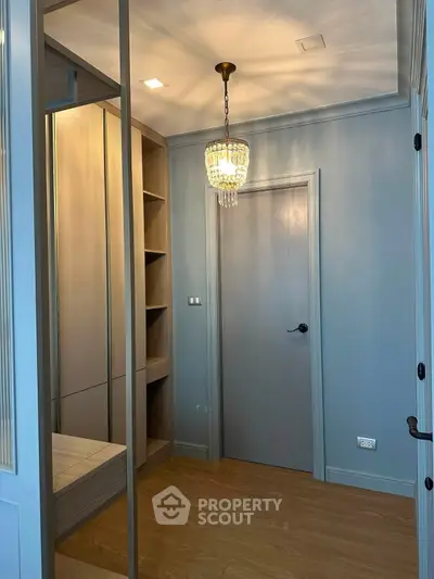 Elegant walk-in closet with chandelier and wooden flooring