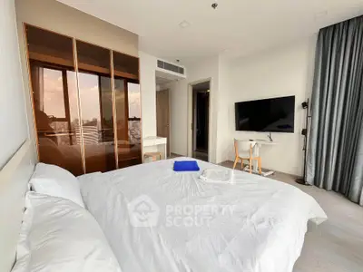 Modern bedroom with city view, featuring sleek furniture and a large TV, perfect for urban living.