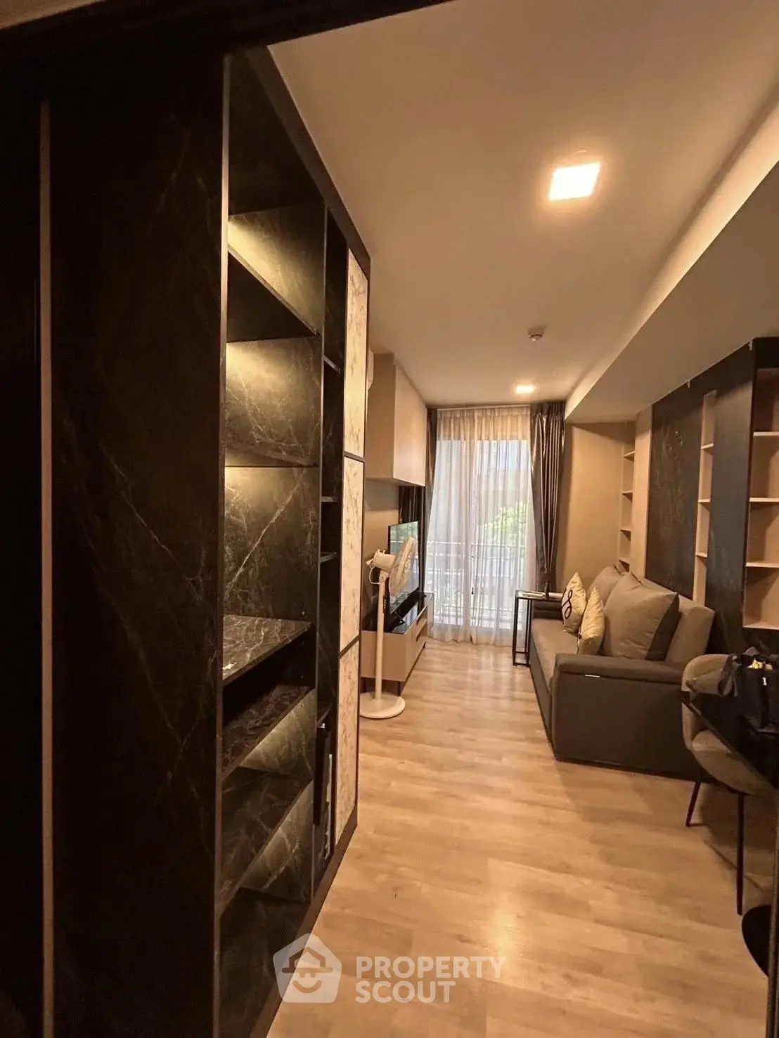 Modern living room with elegant shelving and cozy seating area, featuring floor-to-ceiling windows.