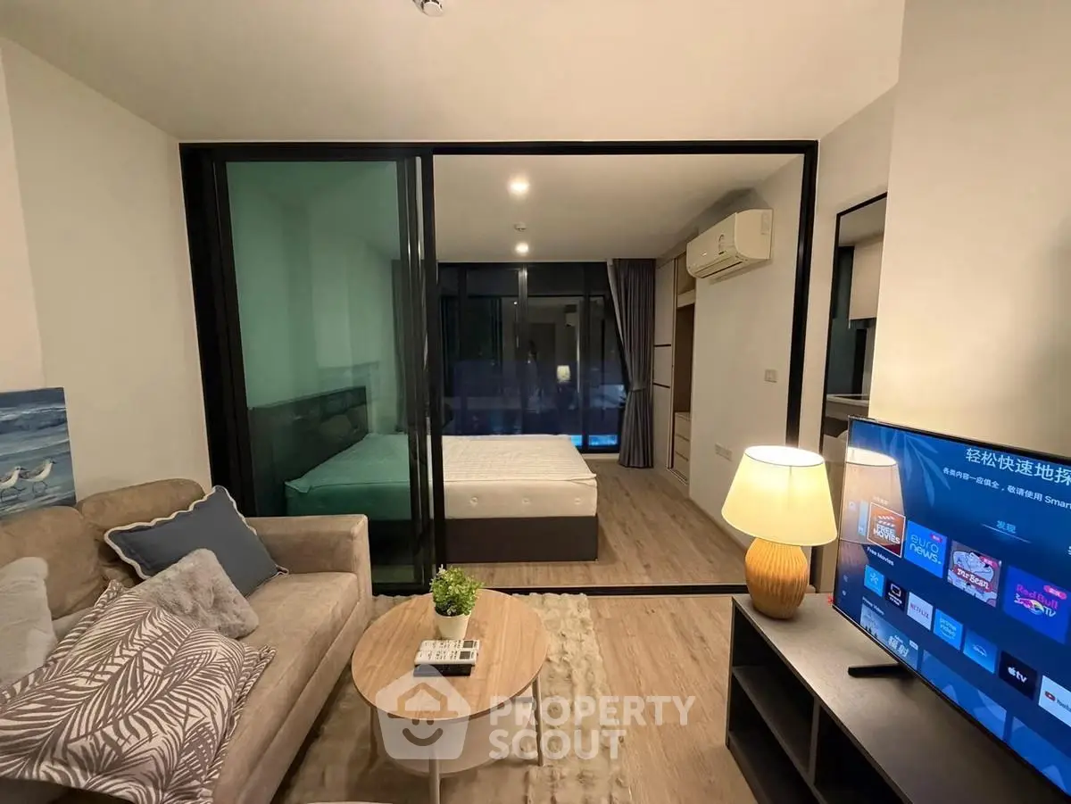 Modern studio apartment with glass partition, cozy living area, and stylish decor.