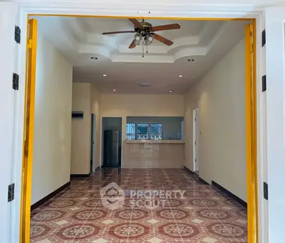 Spacious open-plan living area with decorative flooring and ceiling fan.