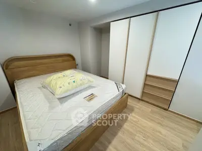 Modern bedroom with wooden bed and spacious wardrobe in a cozy apartment.