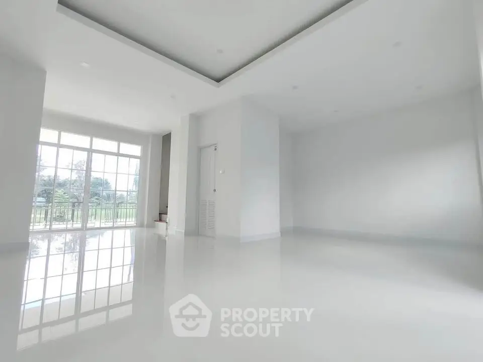 Spacious and bright empty living room with large windows and glossy floors.