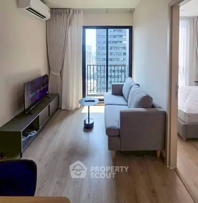 Modern living room with city view, featuring sleek furniture and natural light.