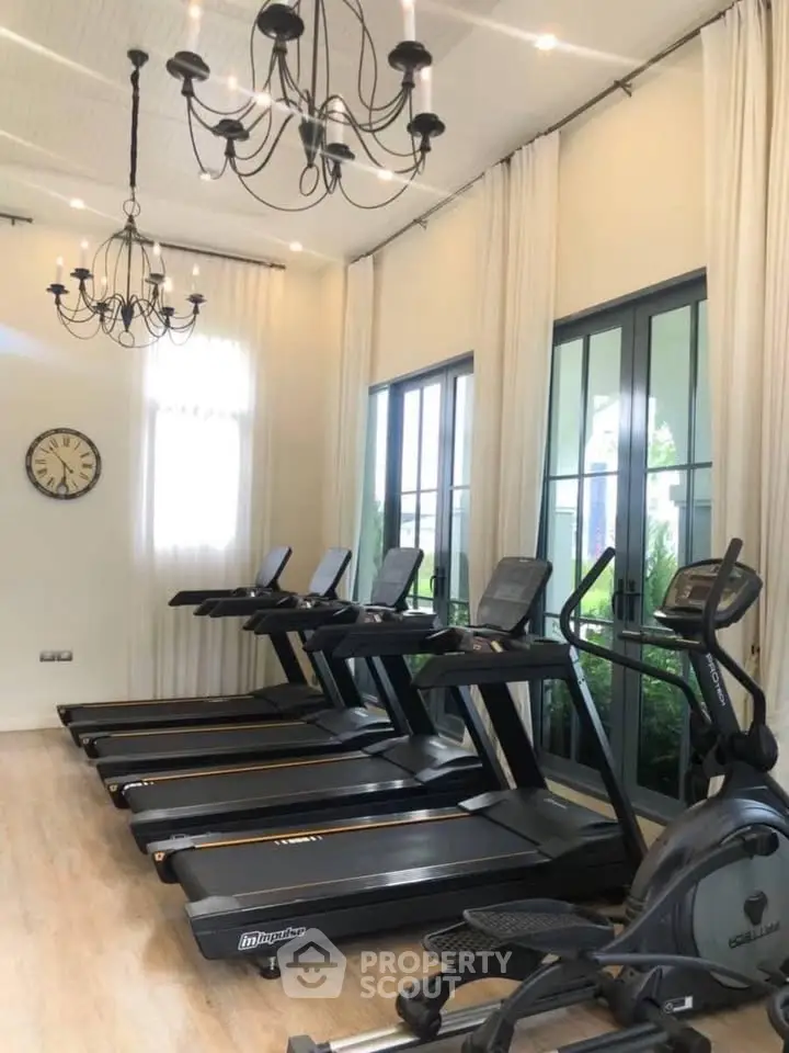 Luxurious home gym with modern treadmills and elegant chandeliers, perfect for fitness enthusiasts.