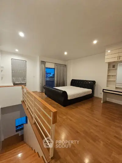Spacious bedroom with elegant bed and wooden flooring, featuring a modern open layout and ample natural light.