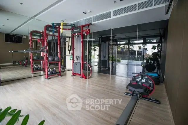 Spacious modern gym with state-of-the-art equipment and mirrored walls in luxury building.
