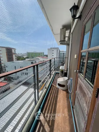 Spacious balcony with city view and safety netting, perfect for relaxation.
