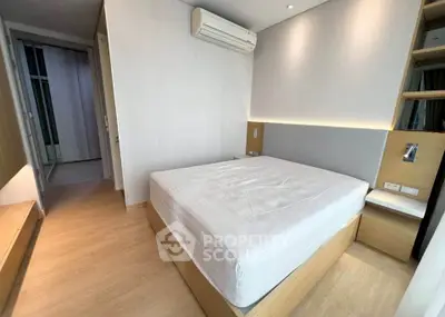 Modern minimalist bedroom with wooden flooring and built-in storage, featuring a sleek air conditioning unit.