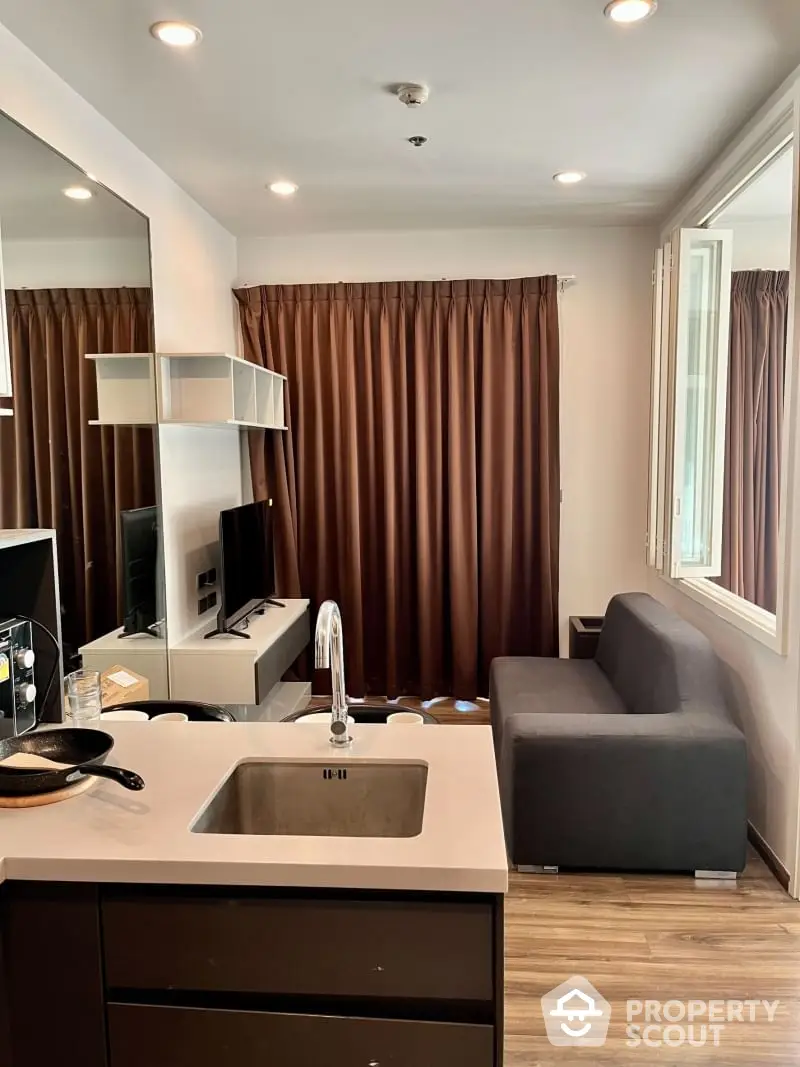 Modern studio apartment with integrated living space, featuring sleek kitchenette, cozy sitting area, and warm wooden flooring, perfect for urban living.