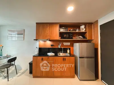 Modern kitchen with wooden cabinets and stainless steel appliances in cozy apartment.