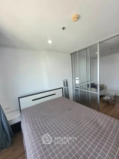 Modern bedroom with sliding glass doors leading to a cozy living area, featuring stylish decor and ample natural light.