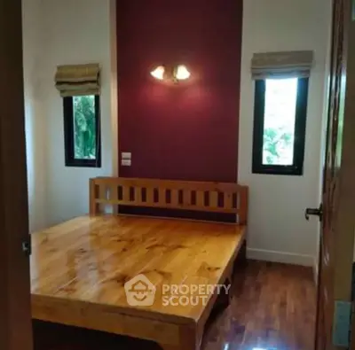 Cozy bedroom with wooden bed frame and natural light from two windows.
