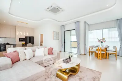 Luxurious open-plan living room with modern kitchen and elegant dining area, featuring stylish decor and ample natural light.