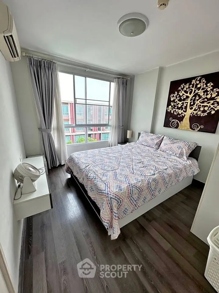 Cozy bedroom with modern decor and large window offering natural light.