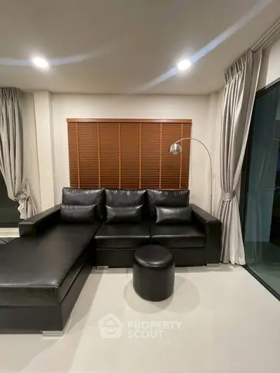Modern living room with sleek black leather sofa and stylish floor lamp