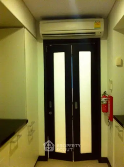Modern kitchen with sleek cabinets and air conditioning unit above door.