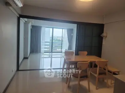 Spacious dining area with wooden table and chairs, leading to a bright balcony with a stunning view.