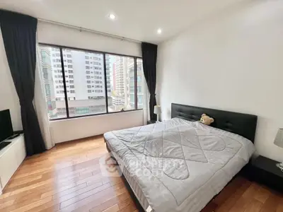 Spacious bedroom with large window offering city view and modern furnishings.