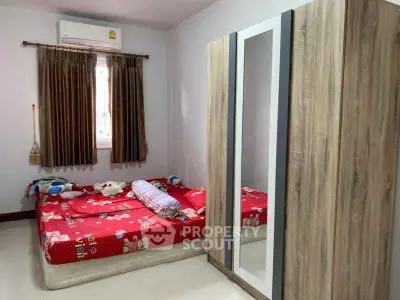 Cozy bedroom with red bedding and wooden wardrobe, perfect for restful nights.