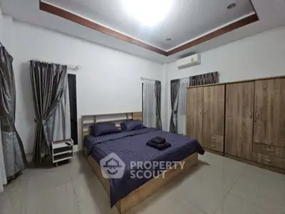 Spacious bedroom with modern furnishings and elegant curtains