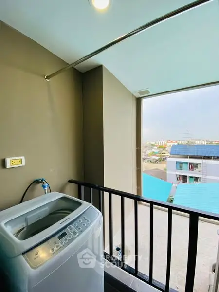 Compact balcony with washing machine and city view, perfect for urban living convenience.